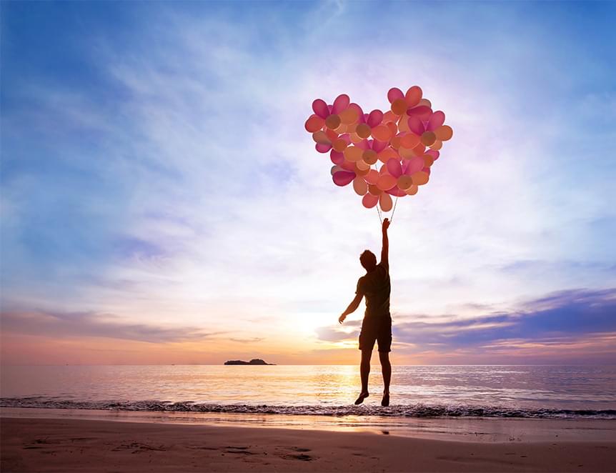 Silhouette holding heart balloons